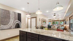 A spacious kitchen with dark cabinets, granite countertops, pendant lighting, and a large abstract painting on the wall. - That Lakefront Taneycomo House - Branson (Branson)