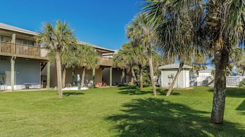 A courtyard with palm trees, a pool, and a building with a balcony.