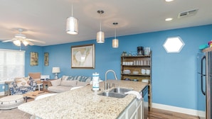A modern kitchen with granite countertops, a built-in sink, and a refrigerator. - The Oasis Pet Friendly Optional Golf Cart (Port Aransas)