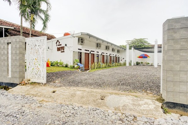 A building with a white facade, multiple doors, and a gravel driveway. - OYO 90124 Oemah Ratu Hostel Syariah (Bandar Lampung)