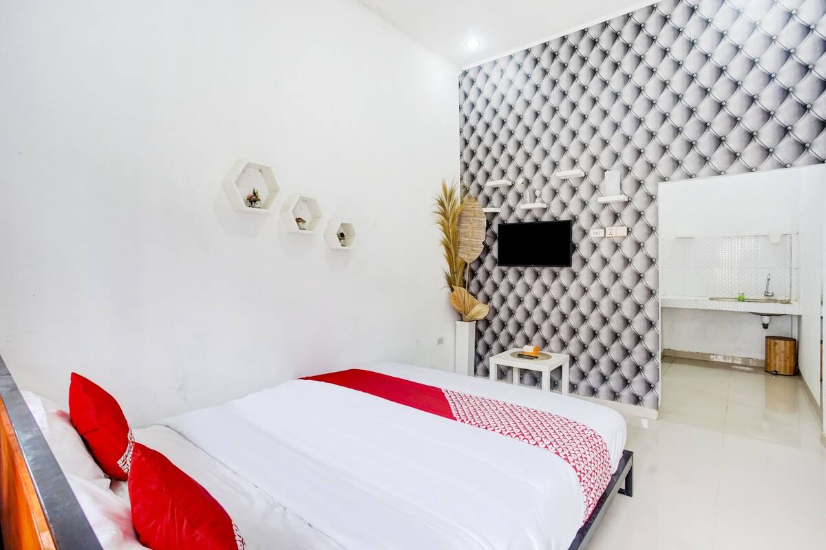 Un dormitorio moderno con cama, tocador y televisor.