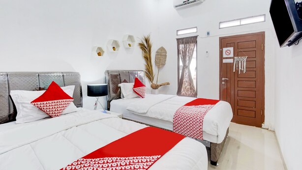A hotel room with two beds, a TV, a door with a sign, and a wall-mounted air conditioner. - OYO 90124 Oemah Ratu Hostel Syariah (Bandar Lampung)