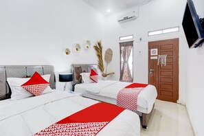 A hotel room with two beds, a TV, a door with a sign, and a wall-mounted air conditioner. - OYO 90124 Oemah Ratu Hostel Syariah (Bandar Lampung)