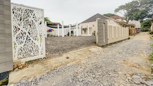 A residential area with a gravel driveway, a white decorative fence, and houses with tiled roofs. - OYO 90124 Oemah Ratu Hostel Syariah (Bandar Lampung)