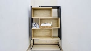 A wooden shelf unit with three shelves, a basket on the middle shelf, and a bottle on the top shelf. - OYO 90124 Oemah Ratu Hostel Syariah (Bandar Lampung)