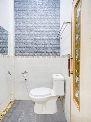 A small, clean bathroom with a white toilet, a shower, and a tiled wall. - OYO 90124 Oemah Ratu Hostel Syariah (Bandar Lampung)