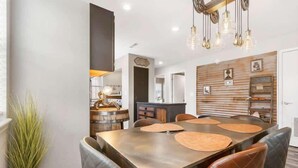 Un espace repas moderne avec une grande table, des chaises en cuir et un luminaire décoratif.