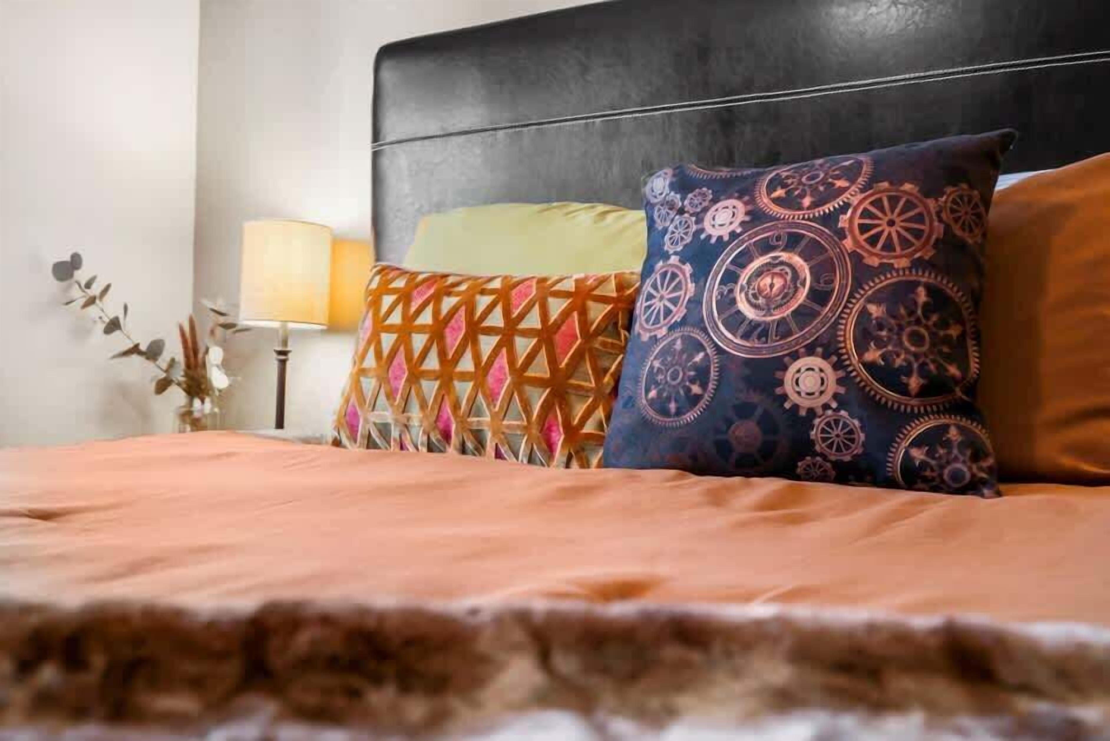 A bed with a patterned headboard, a bedside lamp, and decorative pillows.