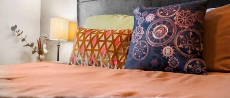A bed with a patterned headboard, a bedside lamp, and decorative pillows.