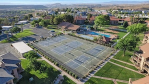 Una cancha deportiva amplia rodeada de edificios residenciales, con vistas despejadas a montañas lejanas.