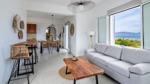 A modern living room with a sofa, a wooden coffee table, and a dining area with chairs and a table. - Blue Harmony villa SEA VIEW heated pool  (ΑΠΟΚΟΡΩΝΑΣ ΧΑΝΙΩΝ)
