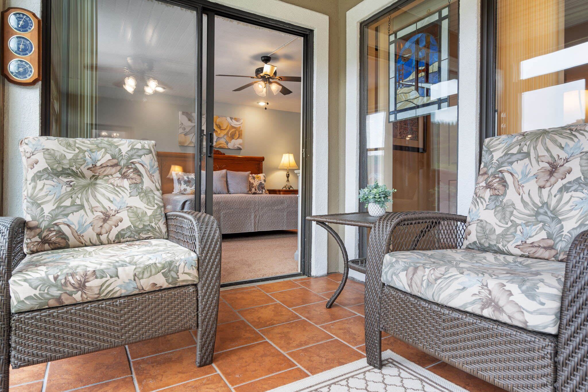 A room with wicker furniture, a bed, and a ceiling fan.