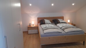 Een slaapkamer met een houten bed, twee nachtkastjes met lampen en een plafondlamp.