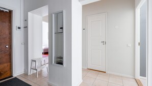 A hallway with a white door, a wooden door, and a white bench. - Historical 3BR Downtown Apartment with Sauna (Tampere)