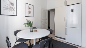 A modern kitchen with a white refrigerator, a dining table with chairs, and framed botanical prints on the wall. - Historical 3BR Downtown Apartment with Sauna (Tampere)