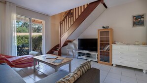 Een moderne woonkamer met een bank, salontafel, televisie en een trap.