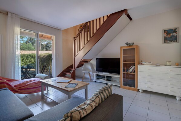 A modern living room with a sofa, a coffee table, a TV, and a staircase.