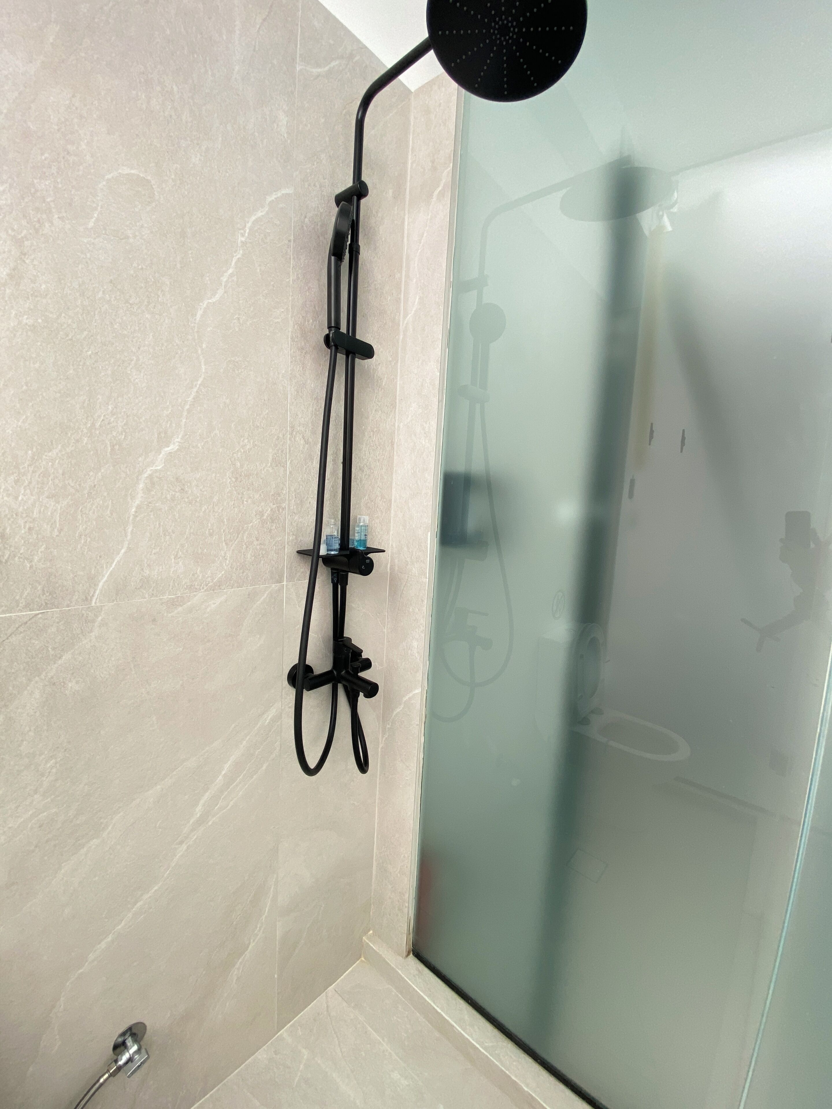 Una ducha con cabezal de ducha manual, un accesorio de ducha manual y un cabezal de ducha instalado en la pared.