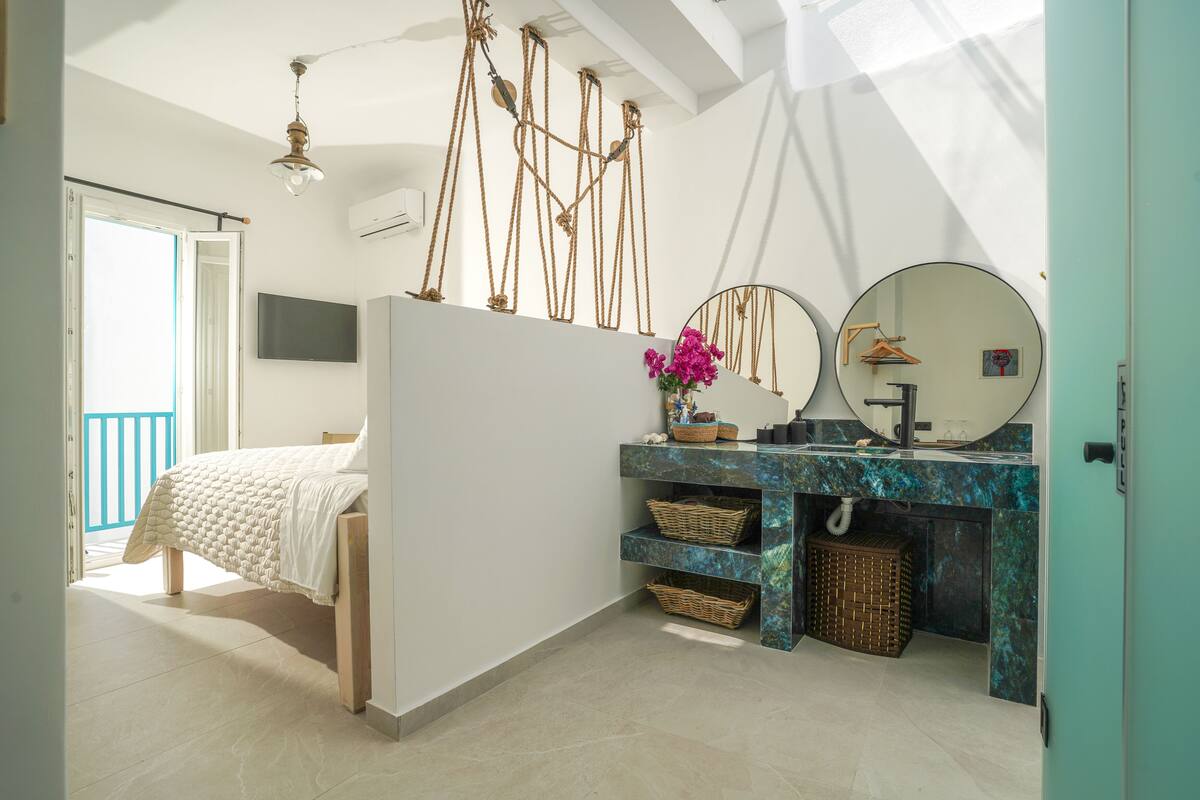 Une chambre à coucher avec un lit, une coiffeuse avec un miroir et un luminaire suspendu.