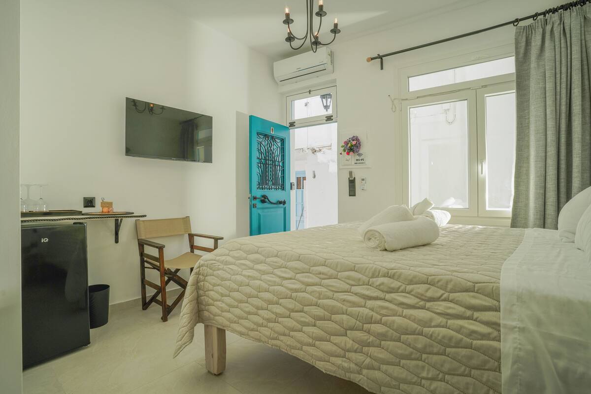 Une chambre à coucher avec un lit, un bureau, une chaise, un miroir et une fenêtre avec des rideaux.