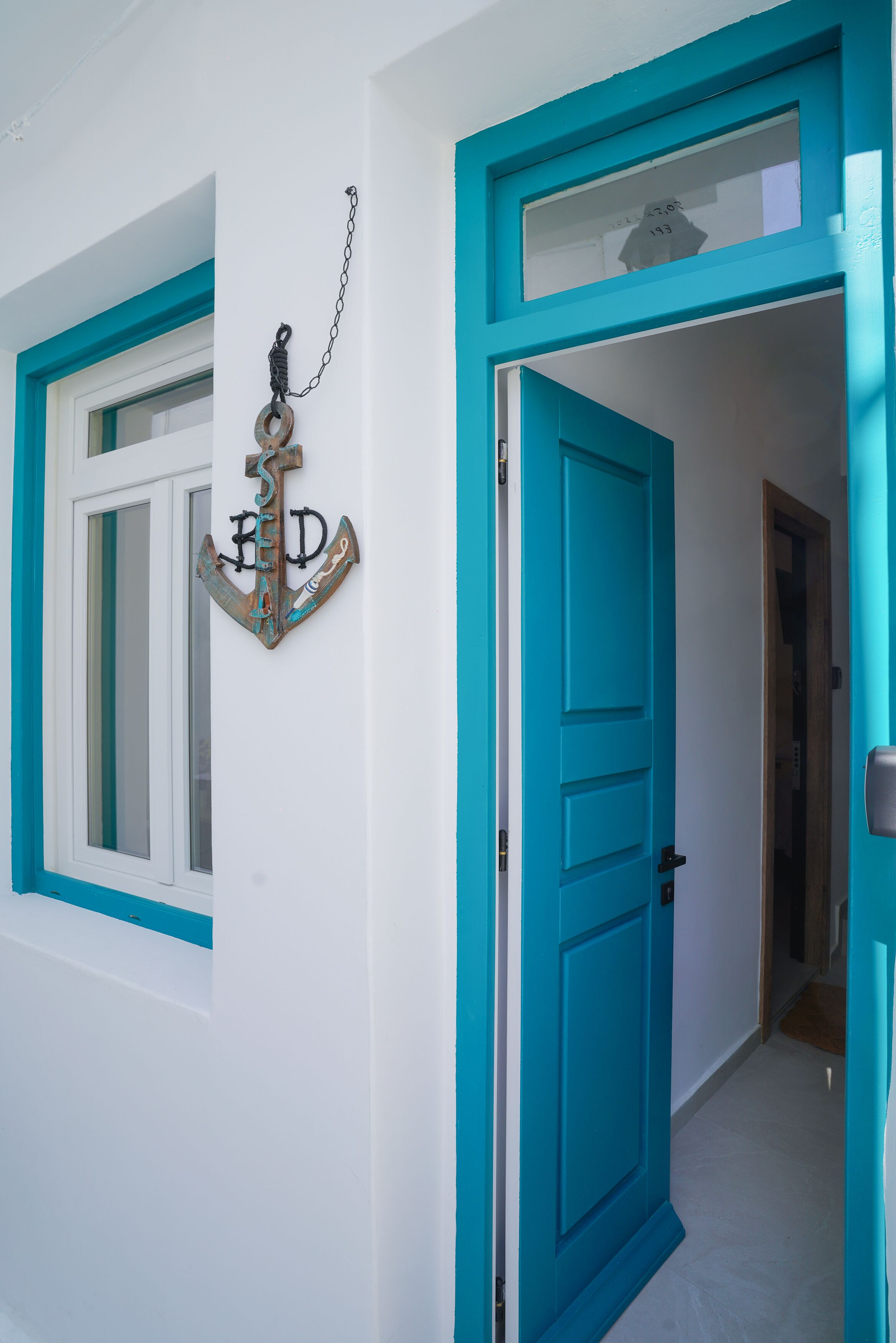 A hallway with a turquoise door and a window with a white frame.
