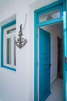 Un pasillo con una puerta turquesa y un ventanal de marco blanco.