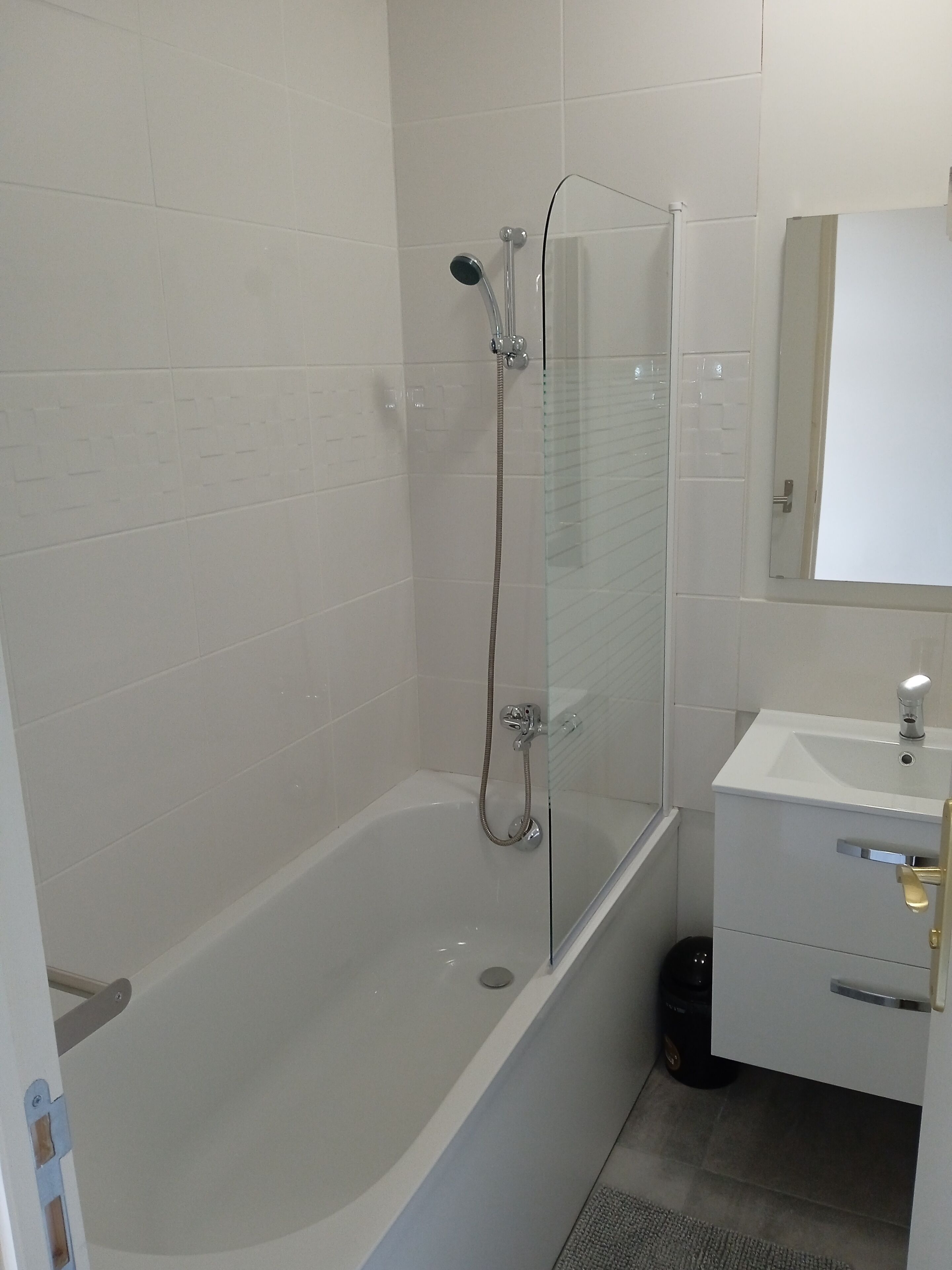 A bathroom with a glass-enclosed shower, a white sink, and a mirror above the sink.