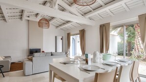 A modern living room with a dining area, white furniture, and large windows with curtains. - 8 adults - 2 kids - Salt marshes and beaches (Noirmoutier-en-l´Ile)