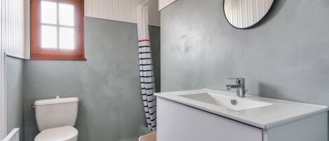 A bathroom with a white toilet, a white sink, and a window with a wooden frame.