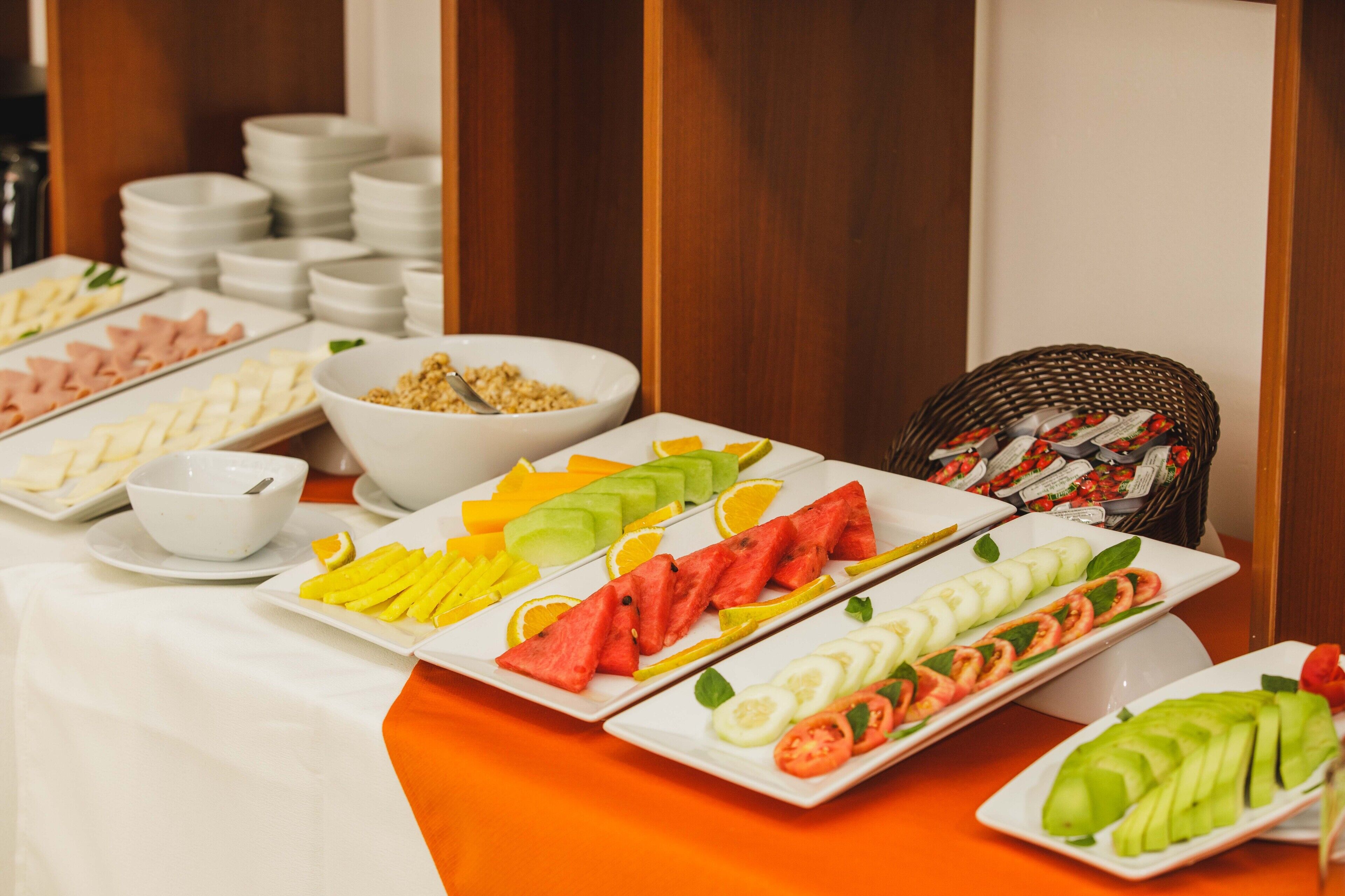 Una mesa de buffet con diversos alimentos, incluyendo frutas, verduras y carnes.