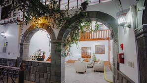 An interior with stone arches, a staircase, and a seating area with cushions. - Quechua Hotel cusco (Cusco)