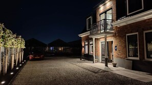 A two-story building with a balcony, a gravel driveway, and a parked car.
