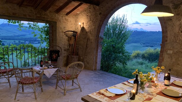 A rustic dining area with a table set for two, overlooking a scenic landscape. - Podere Fontebernardi, authentic Tuscan farmhouse overlooking Pienza. (Monticchielli)