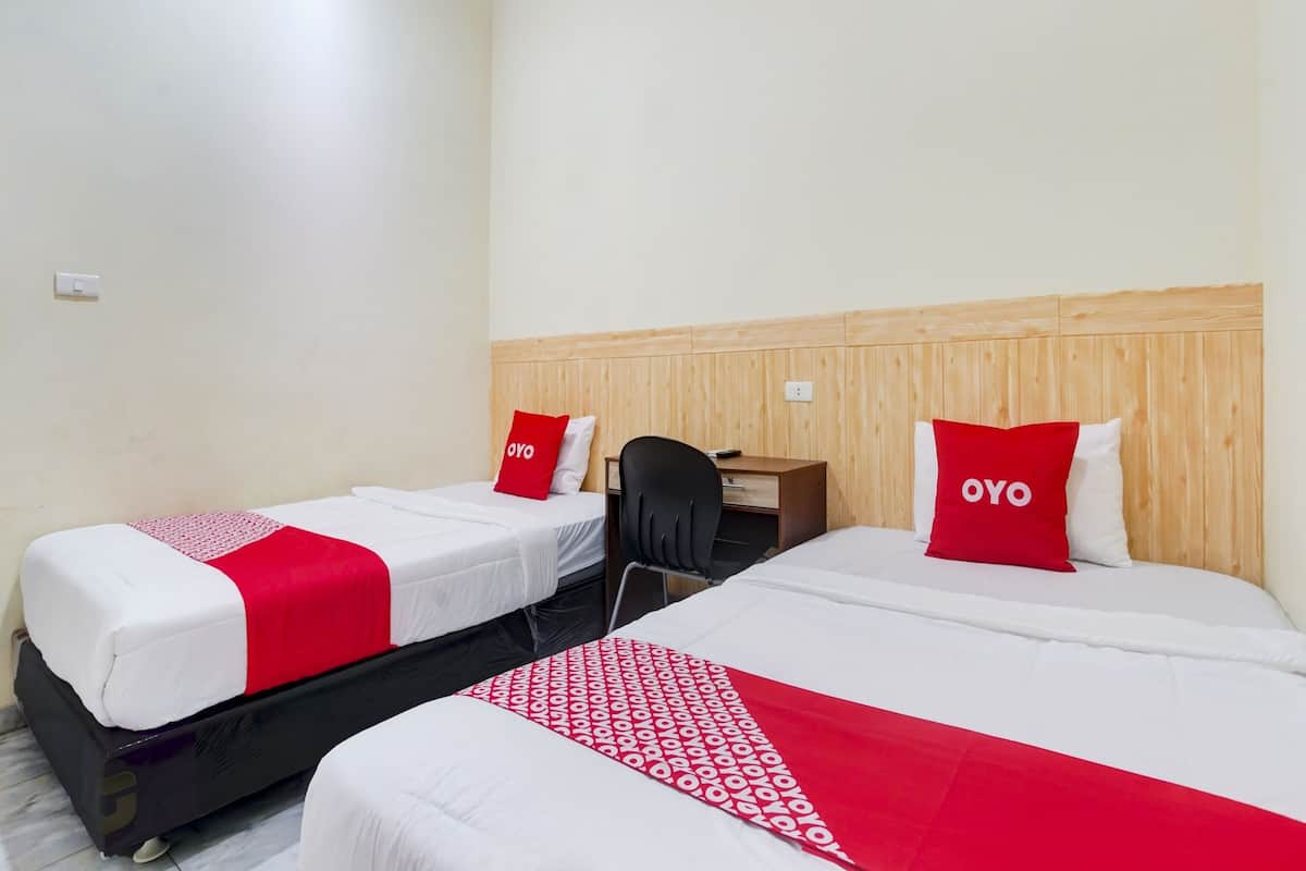Ein Hotelzimmer mit zwei Betten, jeweils mit einer roten und weißen Bettdecke und passenden Kissen.