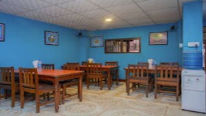 A dining area with wooden tables and chairs, blue walls, and a tiled ceiling. - MeroStay 165 HOTEL RI (Kathmandu)
