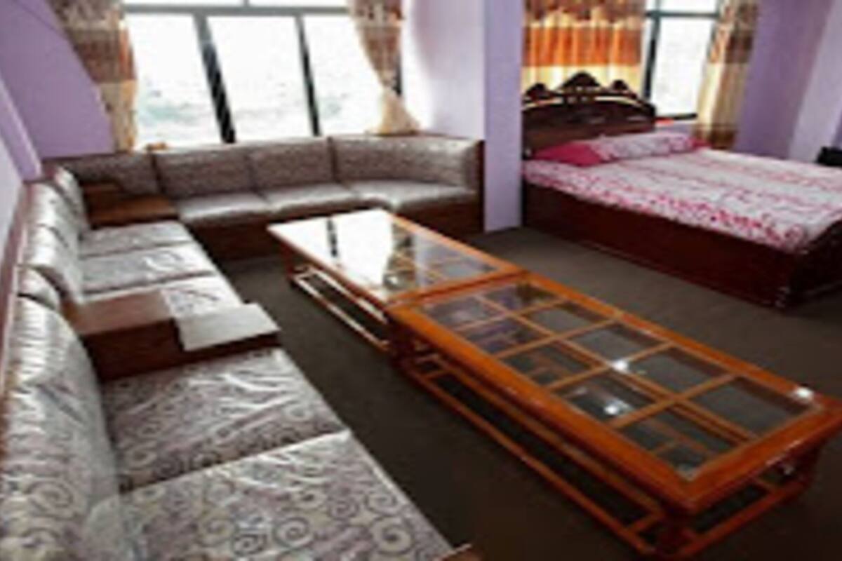 A room with a sofa, a bed, a glass-top coffee table, and a television.