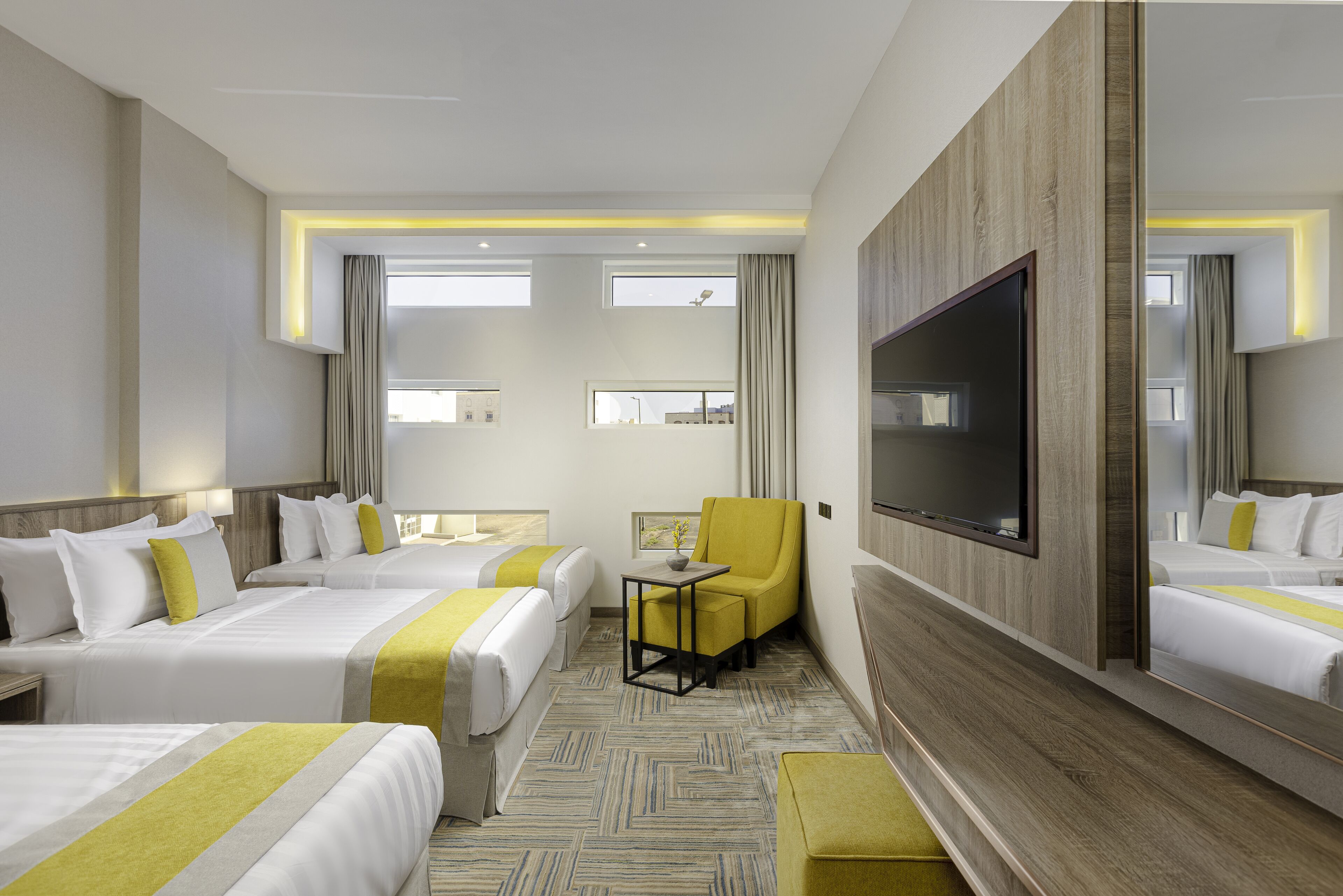 Una habitación de hotel con dos camas, un televisor, una mesita y un espejo.
