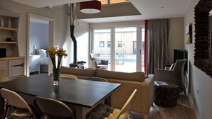 A modern living room with a dining area, a sofa, a coffee table, and a TV. - Modern Barn Conversion, 3 bedrooms (Cheltenham)