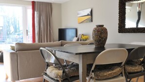 A modern living room with a dining area, a sofa, a TV, and a large vase. - Modern Barn Conversion, 3 bedrooms (Cheltenham)