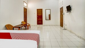 Une chambre d’hôtel comprenant un lit, un bureau, deux chaises, une télévision et un miroir.