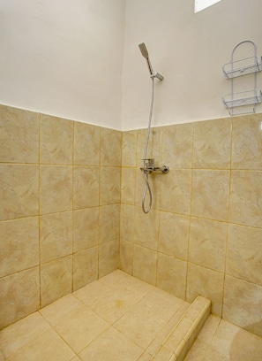 Un petit espace douche équipé d’un pommeau de douche à main, d’un porte-serviettes en métal et d’un mur carrelé.
