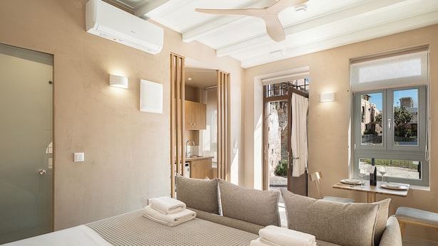 Habitación de hotel con cama, ventilador de techo, ventana con vistas y una puerta.
