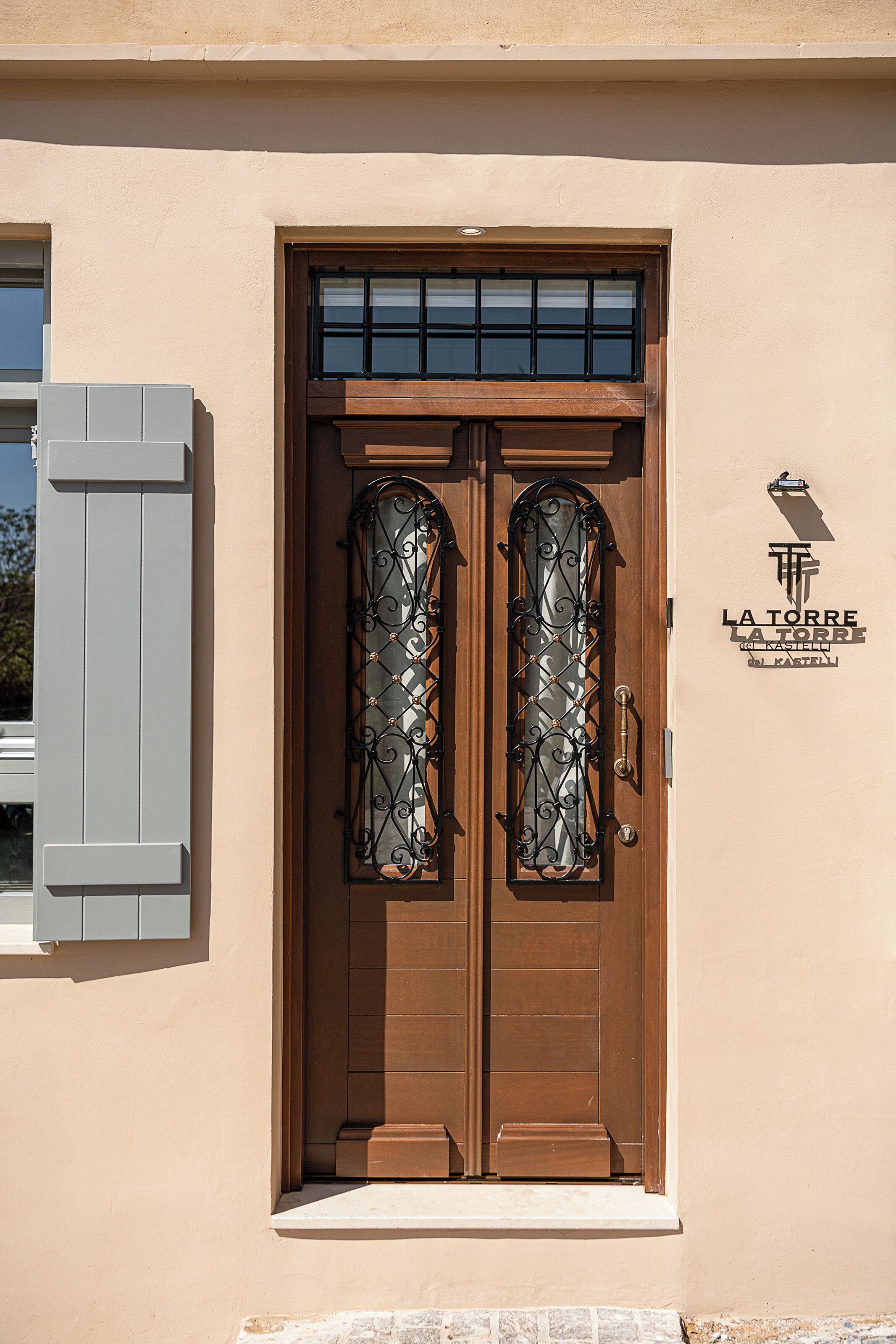 A double wooden door with a metal gate, a beige wall, and a sign reading 'LA TORRE'.