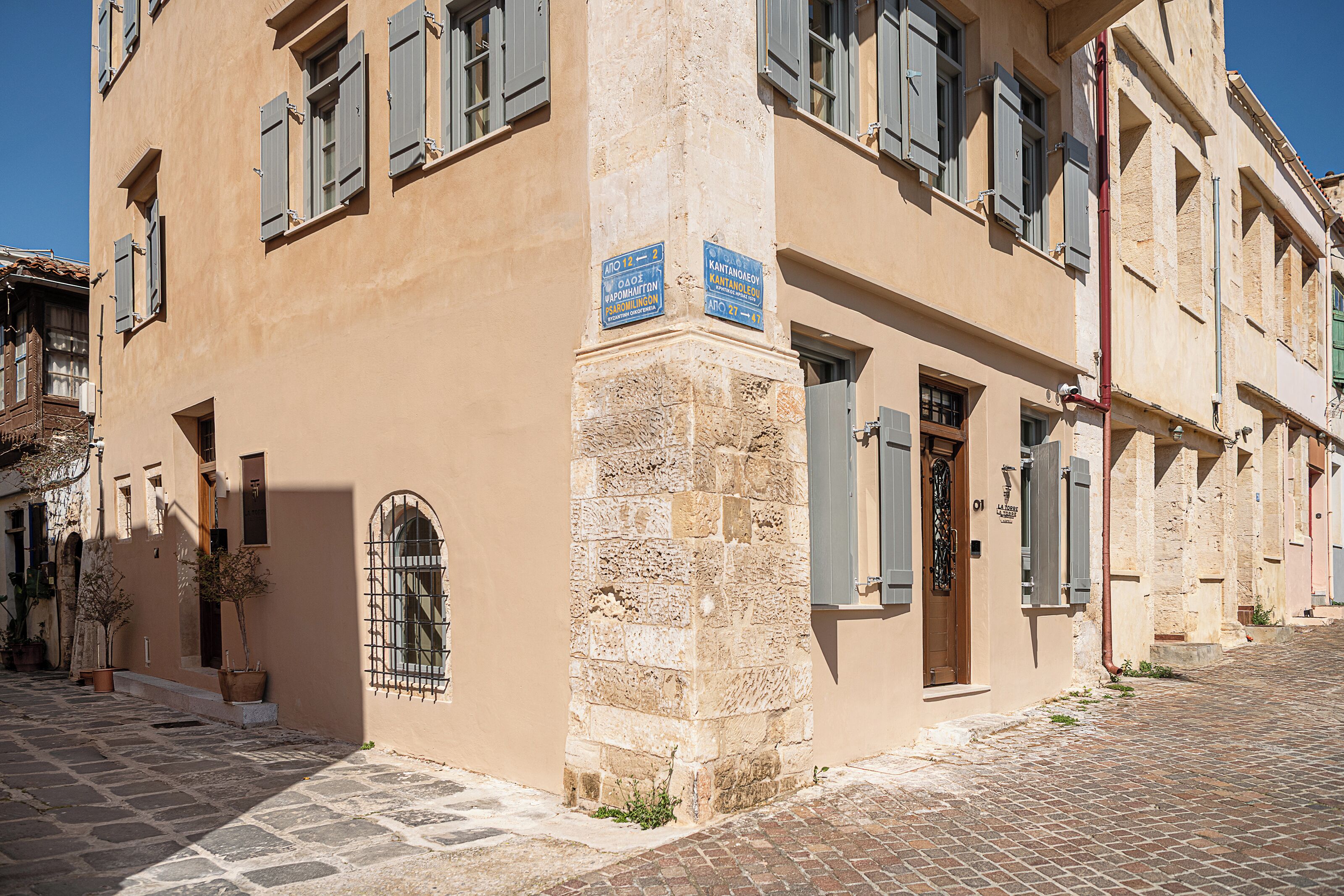 A building with stone and plaster facade, a cobblestone street, and a small door with a window.