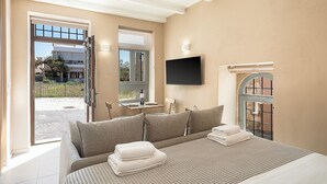 Un dormitorio con cama, televisión, ventana y puerta que da a un balcón.