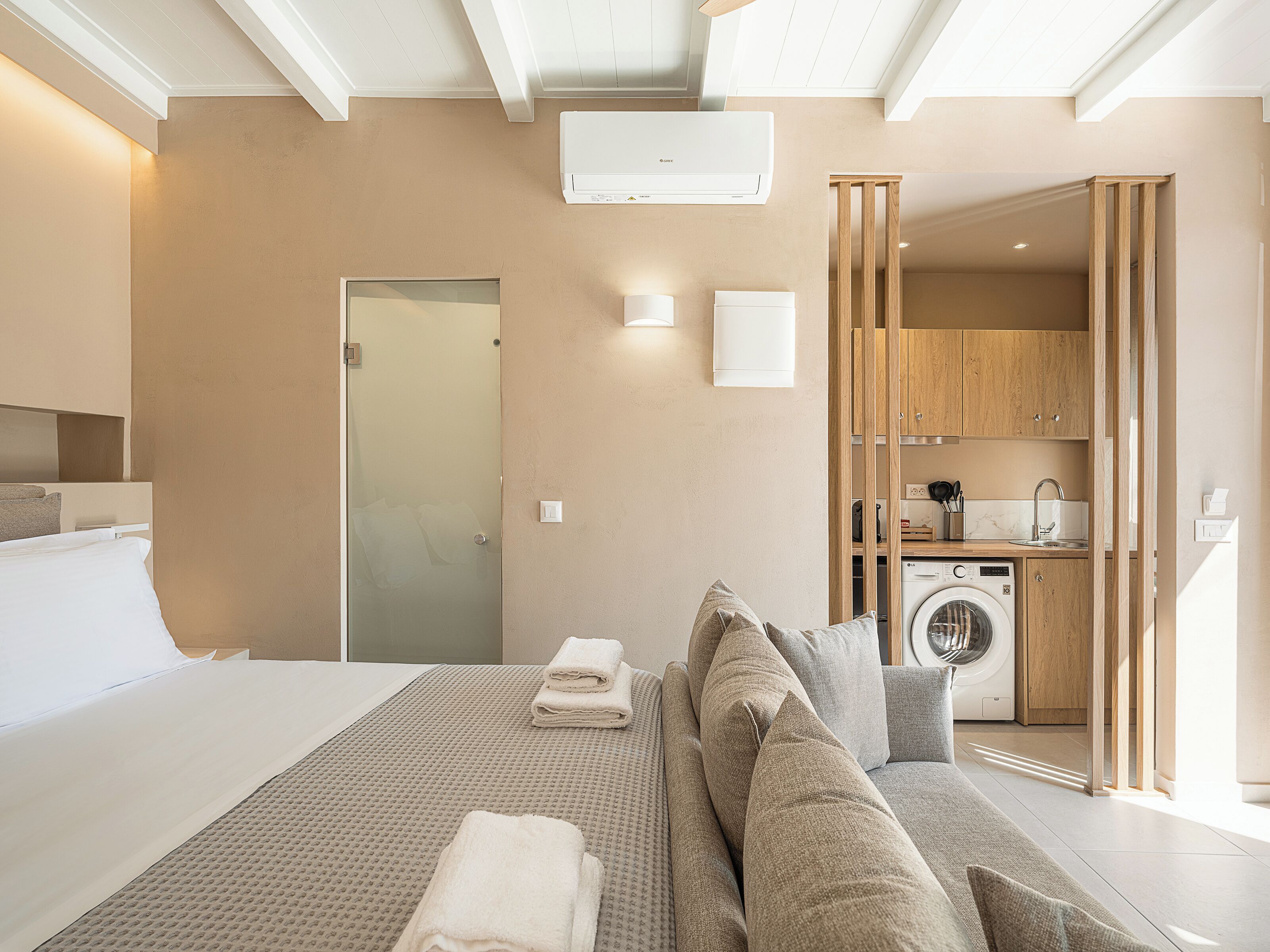 Une chambre d’hôtel moderne équipée d’un lit, d’un canapé, d’un lave-linge et d’un coin cuisine.