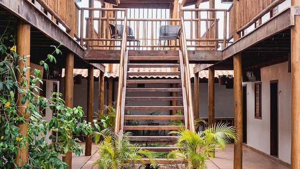 Un bâtiment en bois avec un escalier central, des plantes en pot et un sol carrelé.