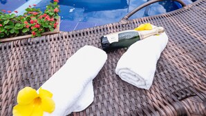 Un fauteuil de relaxation en osier, une bouteille de champagne et une serviette ornée d’une fleur jaune.
