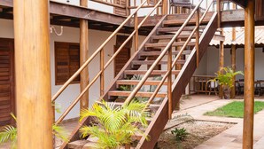 Un escalier en bois menant à un niveau supérieur, entouré de plantes en pot et bordé d’une terrasse carrelée.