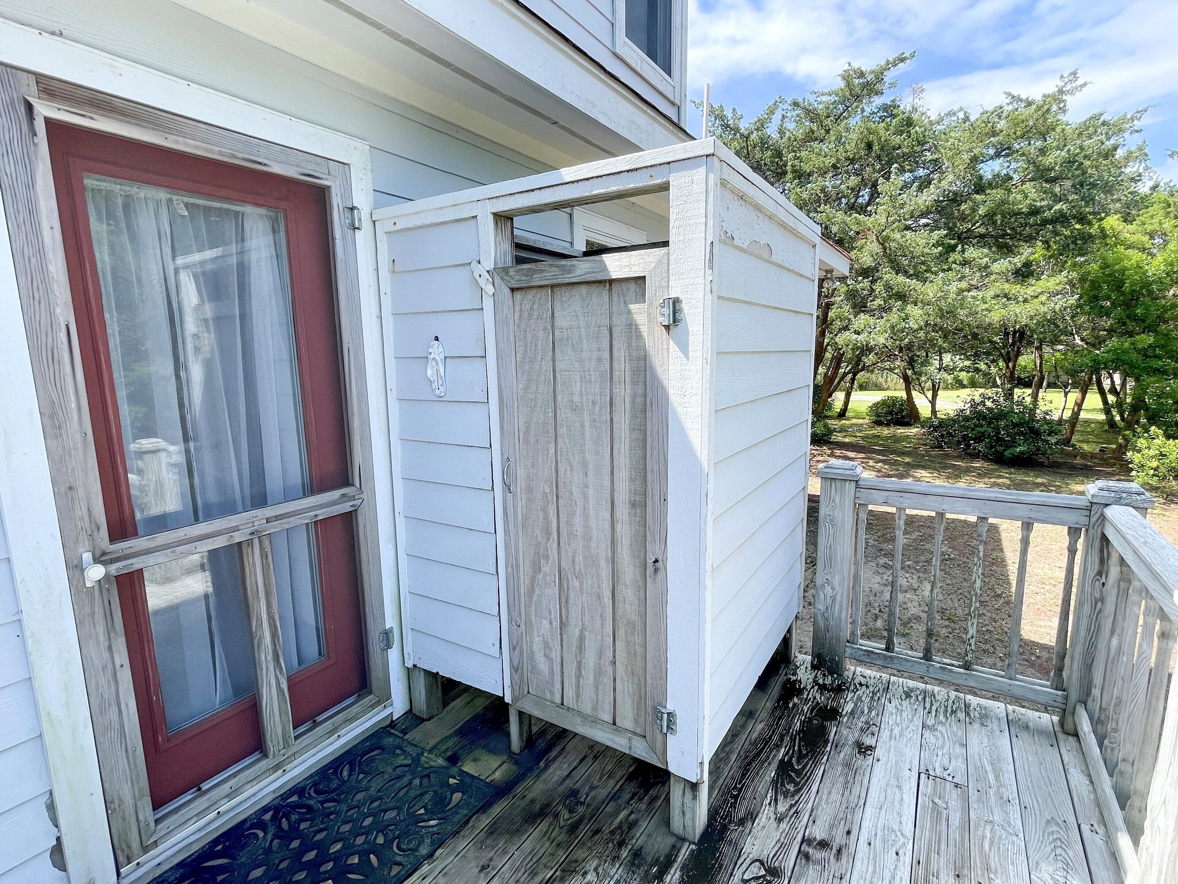 A wooden deck with a white door and a small shed.